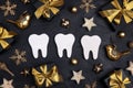 White teeth with gold decorations and gift boxes on black background. Dentist Merry Christmas and New Year concept