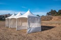 White tent in brown grass field under blue sky Royalty Free Stock Photo