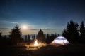 Magical nightfall view of starry sky over campsite in the mountains.