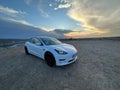 White Tesla model 3 parked outdoors at sunset