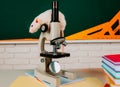 White test rat sitting on microscope. Laboratory rat in a lab. Concept - testing of drugs, vaccines, laboratory animals Royalty Free Stock Photo