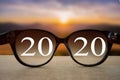 2020 white text with black eye glasses on wooden table over blur autumn landscapes. Business vision happy new year Royalty Free Stock Photo