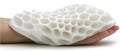 A white, textured object with a honeycomb pattern is held in a hand. Royalty Free Stock Photo