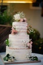 White three tiered naked wedding cake with tiny pink, orange roses decoration Royalty Free Stock Photo