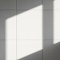 White tiles arranged in a grid pattern with sunlight casting diagonal shadows across the surface. Royalty Free Stock Photo
