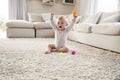White toddler boy on the floor in sitting room raising arms Royalty Free Stock Photo