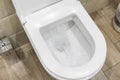 White toilet bowl in a bathroom. Closeup view of a flushing white toilet. The water swirls in the toilet bowl. Royalty Free Stock Photo