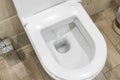 White toilet bowl in a bathroom. Closeup view of a flushing white toilet. The water swirls in the toilet bowl. Royalty Free Stock Photo