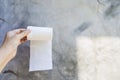 White toilet paper roll in girl hand with space on cement wall background Royalty Free Stock Photo