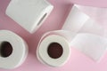 White toilet paper rolls on pastel pink background. Space for text.