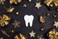 White tooth with golden decorations and gift boxes on black background. Dentist Merry Christmas and New Year concept Royalty Free Stock Photo