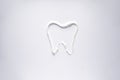 White toothpaste in the form of a tooth on a white background, close-up