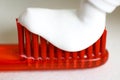 White toothpaste on an orange toothbrush. Macro. Closeup. Isolated on a white background Royalty Free Stock Photo