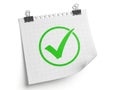 A white torn paper note with a bright green checkmark inside a circle held by two binder clips Royalty Free Stock Photo