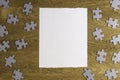 White torn paper piece surrounded by puzzle pieces on wooden background. Top view. Copy space for text Royalty Free Stock Photo