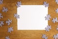 White torn paper piece surrounded by puzzle pieces on wooden background. Top view. Copy space for text Royalty Free Stock Photo