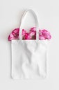 White tote bag mockup with a bouquet of a roses on a white table