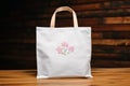 White Tote Bag with Pink Floral Design on Wooden Surface