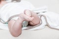 White towel around cute newborn feet. Close up picture of new born baby feet on a white sheet