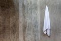 White towel is hanging on the exposed concrete wall in the bathroom. Royalty Free Stock Photo