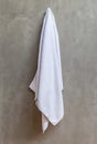 The white towel is hanging on a hanger with concrete wall in the Royalty Free Stock Photo