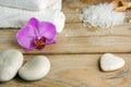 White towels, bath salts and stones for a hot massage on a wooden table.