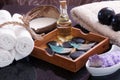 White towels knitted next to the set for massage from Bian stones, aroma oil and violet salt, in a wooden box a set of