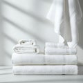 White towels are neatly stacked on a surface, with sunlight creating soft, linear