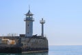 The white tower of a small old lighthouse on a rocky promontory. In the background is a calm blue sea and sky. Yalta Royalty Free Stock Photo