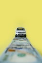 White toy car on money road on yellow background Royalty Free Stock Photo