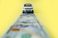 White toy car on money road on yellow background Royalty Free Stock Photo