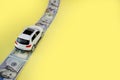 White toy car on money road on yellow background with copy space Royalty Free Stock Photo