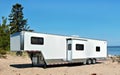 White toy hauler travel trailer camping on the sandy shore of beautiful lake Superior Royalty Free Stock Photo