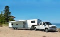 White toy hauler travel trailer camping on the sandy shore of beautiful lake Superior