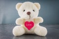 White toy teddy bear with heart on a gray background. The symbol Royalty Free Stock Photo