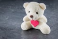 White toy teddy bear with heart on a gray background. The symbol Royalty Free Stock Photo