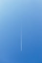 White trace of smoke from flying airplane. Vertical image. Plane flying in blue sky and living white track line smoke. Aircraft Royalty Free Stock Photo