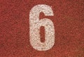 White track number on red rubber racetrack, texture of running racetracks in small outdoor stadium