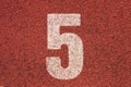 White track number on red rubber racetrack, texture of running racetracks in small outdoor stadium