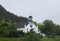 Church with bell tower in a lush green landscape of grass and forest