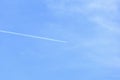 White airplane trail in a bright blue sky. The plane, leaving a trail, flies in the spacious clean bright blue skie