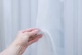 White translucent curtain tulle in hand of a Caucasian woman