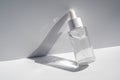 A white transparent bottle with serum in the rays of the sun.