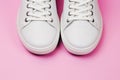 White trendy sneakers on pink pastel background. Front view