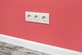 White triple outlet on pink wall