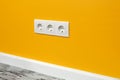 White triple outlet on yellow wall