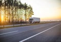 White truck with isotherm semitrailer transports frozen fruits and vegetables on the highway against the backdrop of a sunny Royalty Free Stock Photo