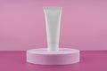 White tube of cosmetic product on podium pedestal on pink background. Cream bottle, lotion, mousse showcase for skincare