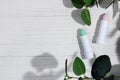 White tubes of pink and green lip balm with aloe, against dryness, to protect and nourish lips, on a white wooden background with