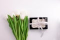 White tulip flowers and black gift box on light background flat lay. Place for text 8 March Happy Womens Mothers Day Royalty Free Stock Photo